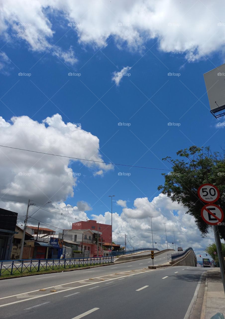 Um dia belíssimo e, de trânsito livre no centro urbano: Céu azul anil,  nuvens carregadas fazendo correografias e, a árvore balançando suas folhas batendo palmas.