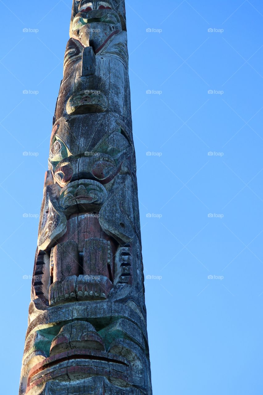 West coast (Canada) carved wood totem pole against vivid clear blue sky, Vancouver, BC 