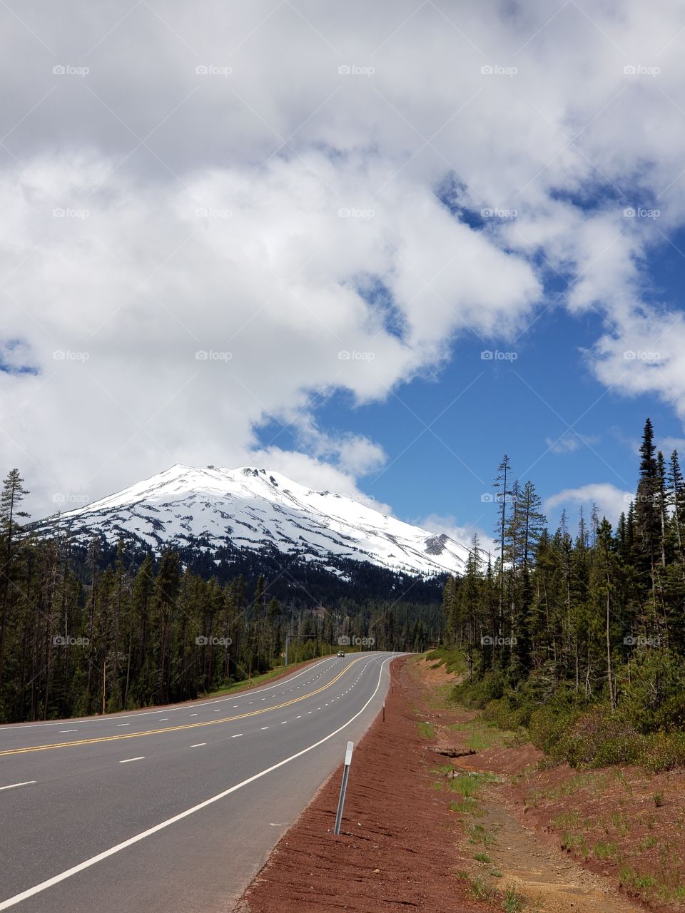 Sunlight begins to illuminate Mt. Bachelor in Oregon's Cascade Mountain Range as the blue skies break through the clouds on a beautiful summer day.