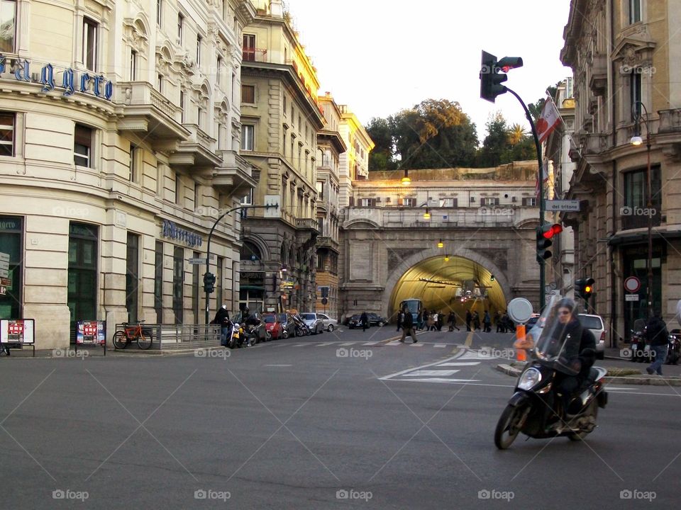 Italian streetscape with motorcyclist making turn and a tunnel beyond 
