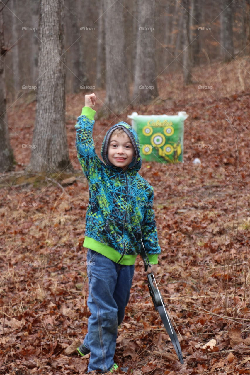 Portrait of a boy holding arrow in forest