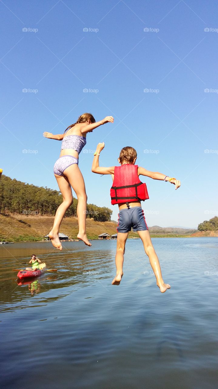 Jumping into the lake under blue sky.