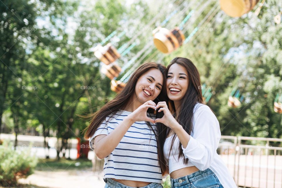 Young women with long hair friends having fun at amusement park