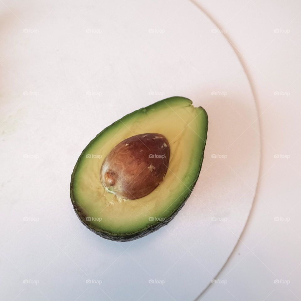 Half green avocado and pit