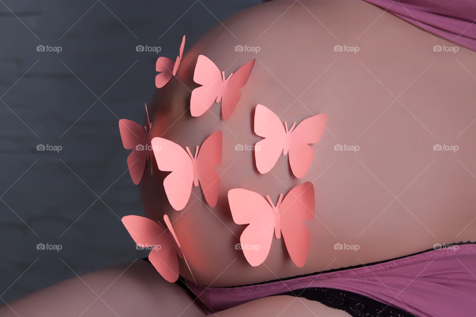 Pregnant woman's belly with paper butterflies