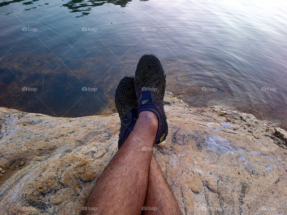 resting feet on some rocks at the water