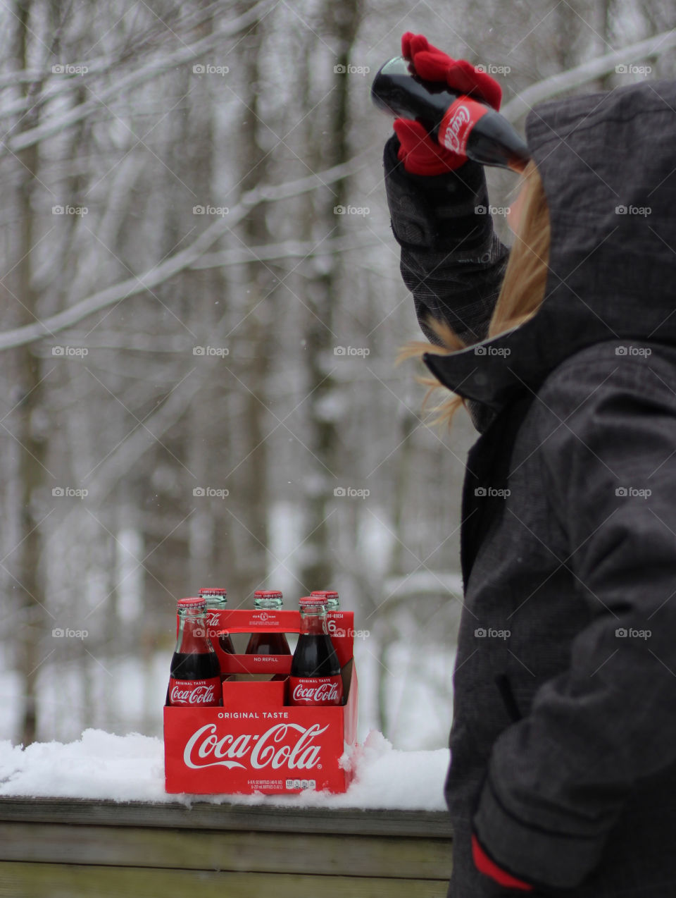 Woman taking a drink of a Mini Coca Cola with 6 pack of minis outdoors in the snow