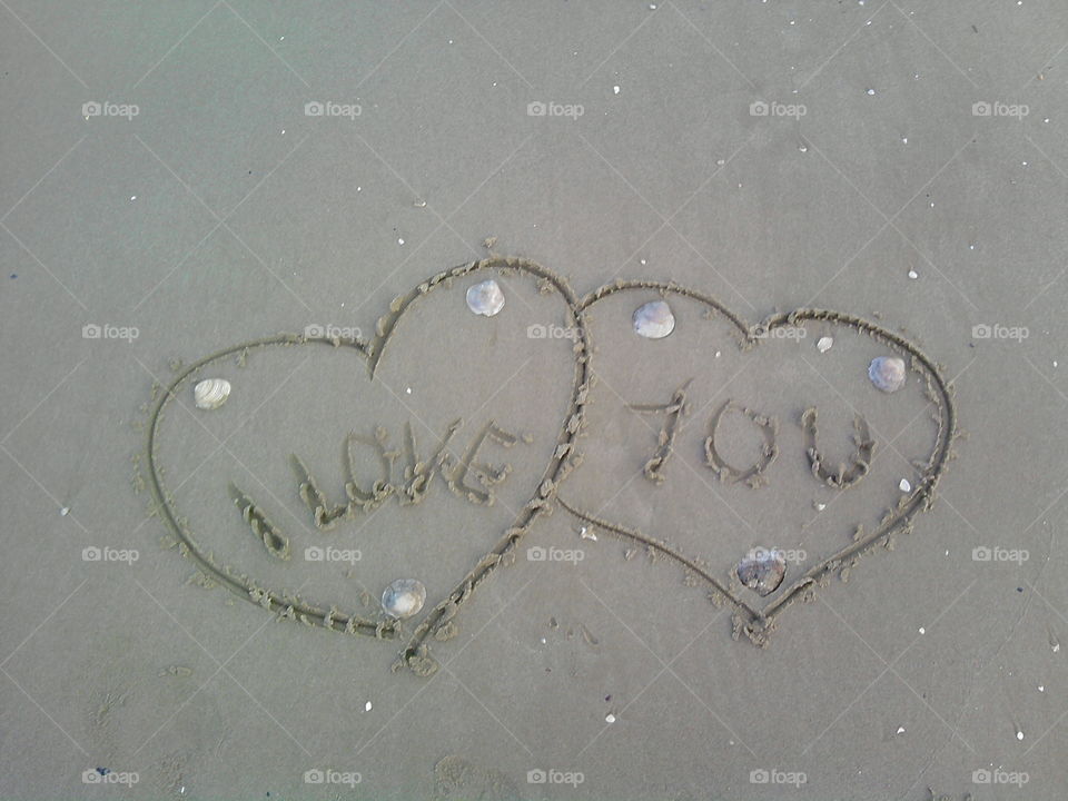 Two hearts drawn in the sand and written I love you