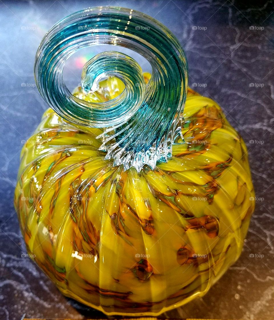 Blown glass pumpkin, stem spiraled blue, variations of color throughout pumpkin itself.