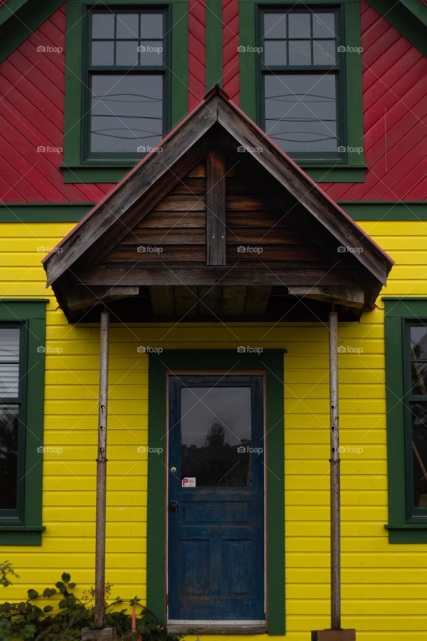 A vibrant yellow, green and red house with a teal door. This home is in a nearby village known for its unique style and striking colour combinations.