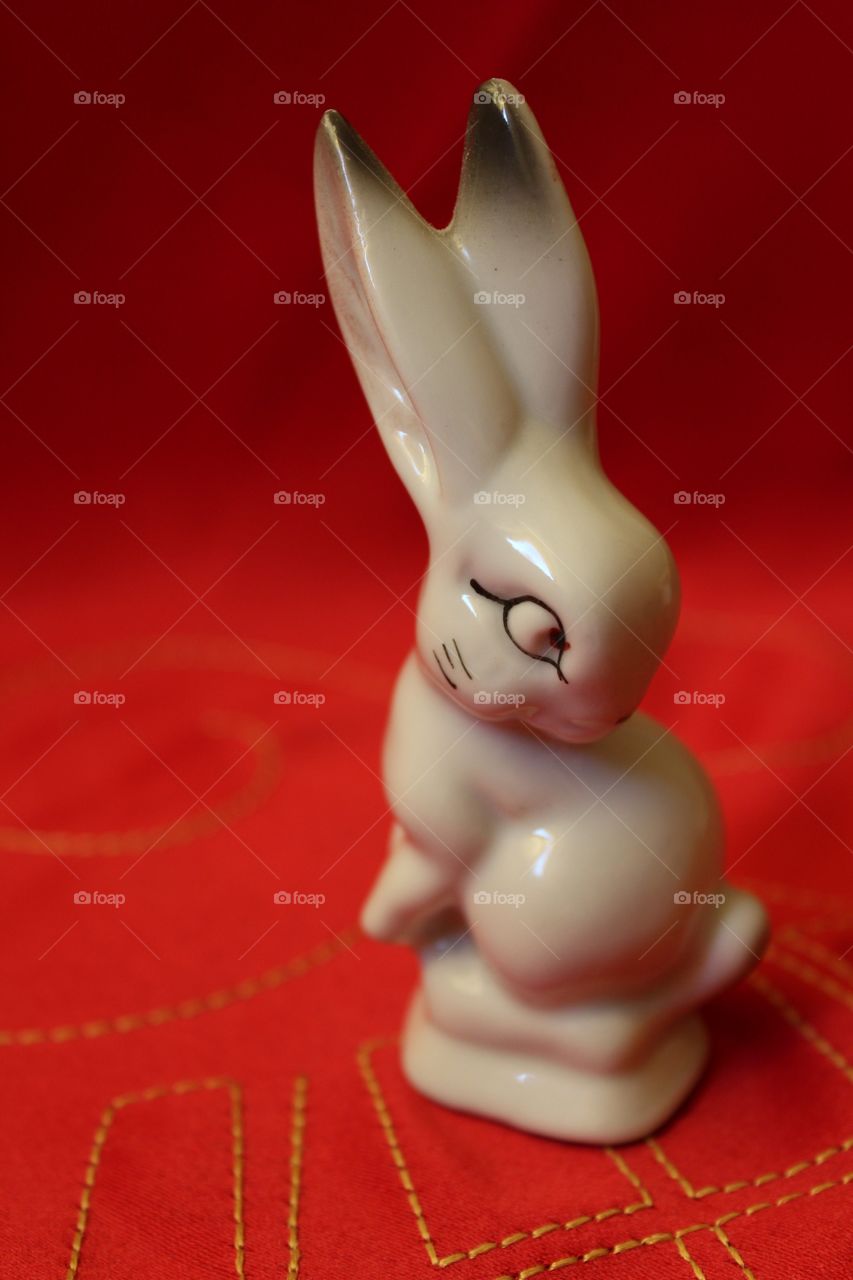 Miniature porcelain white bunny on a red background