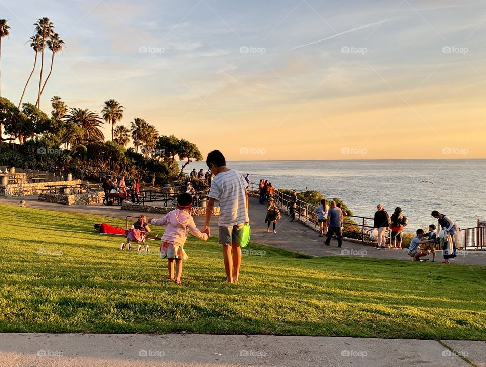 Big brother sweetly guiding little sister near the beach