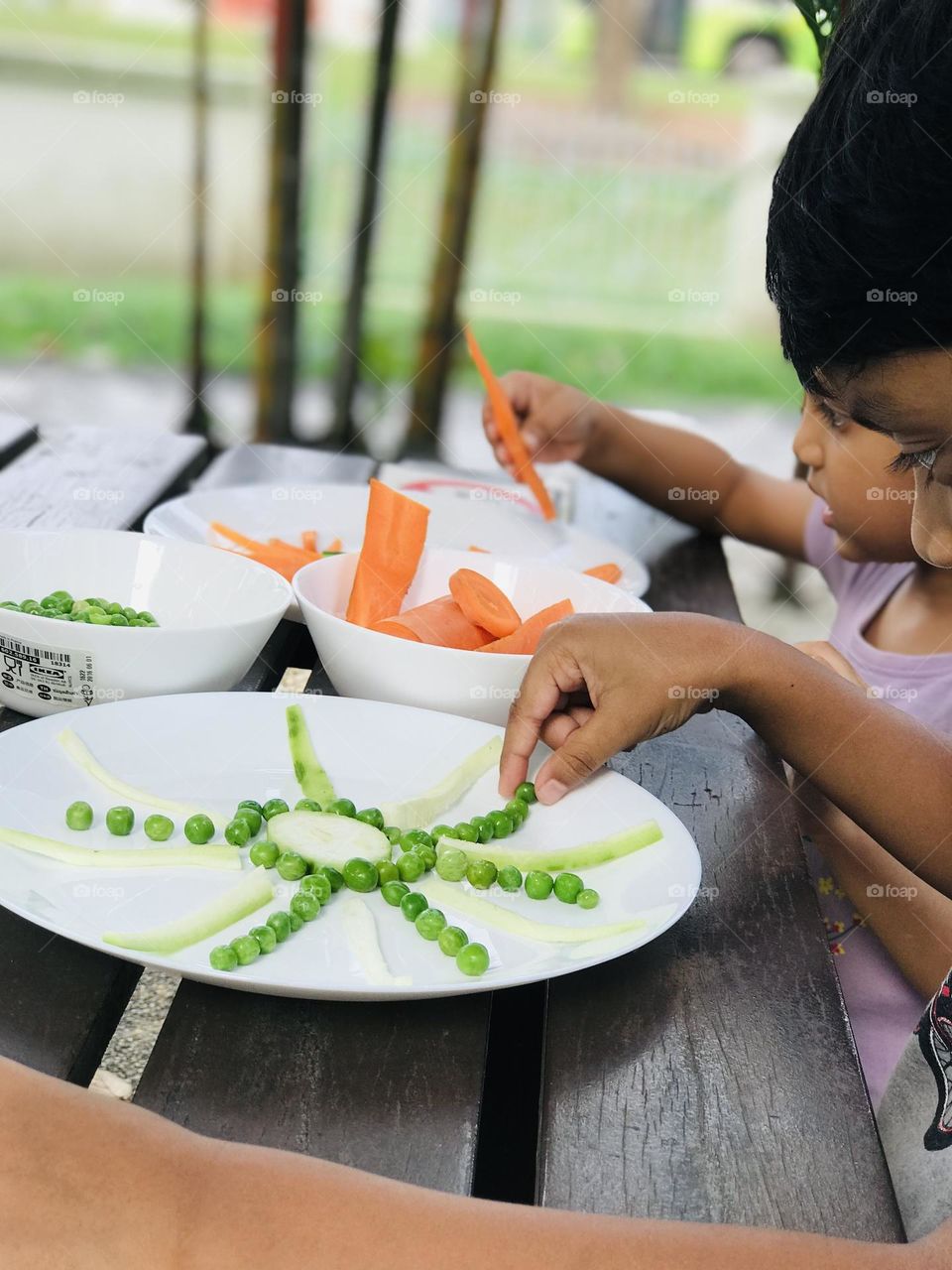 Kids creating sun and other shapes with the help of vegetables like carrots and Greenpeace 