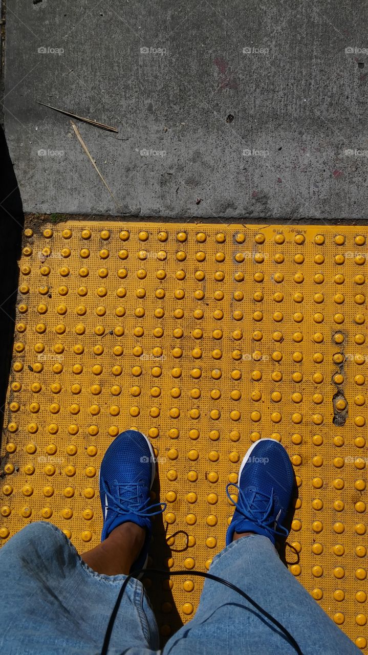 blue tennis shoes on a yellow crosswalk