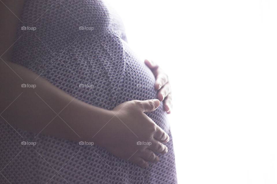 Pregnant Asian woman with tanned skin holding her belly