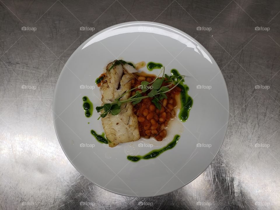 Bright and colorful, professionally plated fish dinner with cilantro oil and a bean salad.