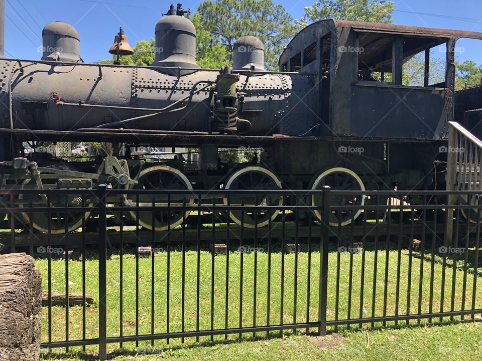 A very old train in Ponchatoula, Louisianna behind a wrought iron fence. 