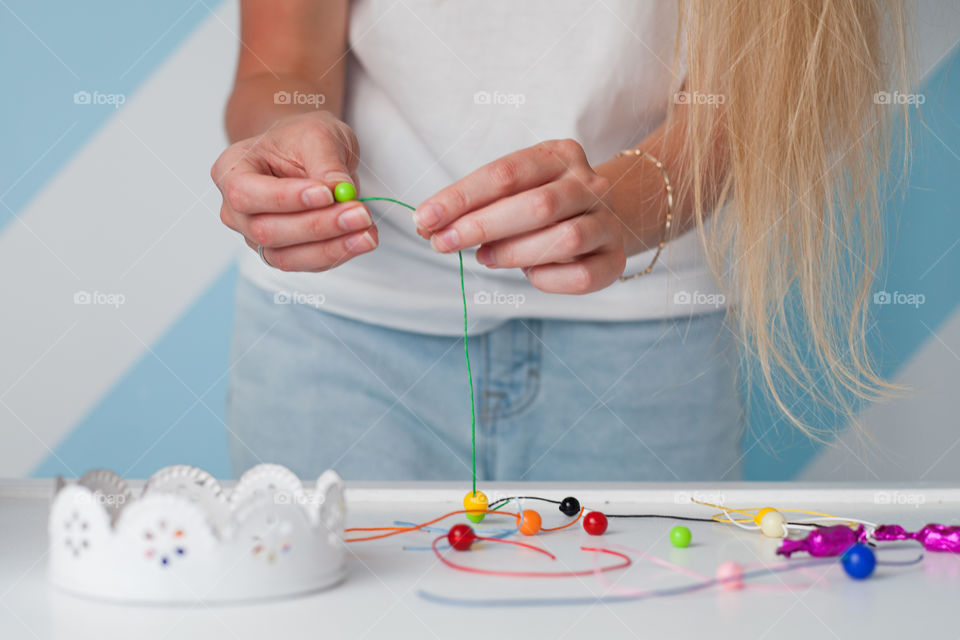 woman makes a beaded bracelet