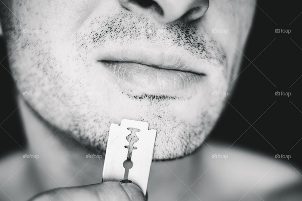 Close-up of beard man' face with stainless razor blade
