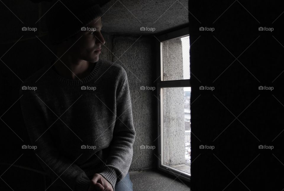 Close-up of a young man sitting near window