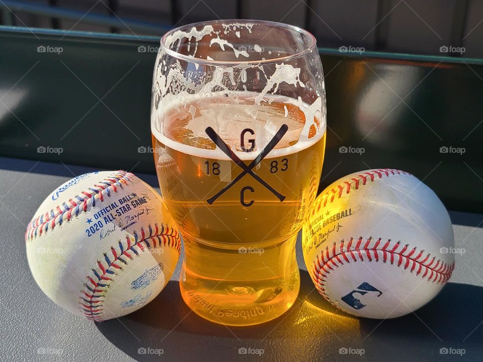 Cold glass of beer with two baseballs at the ballpark, there is nothing better than beer and baseball on a warm afternoon 
