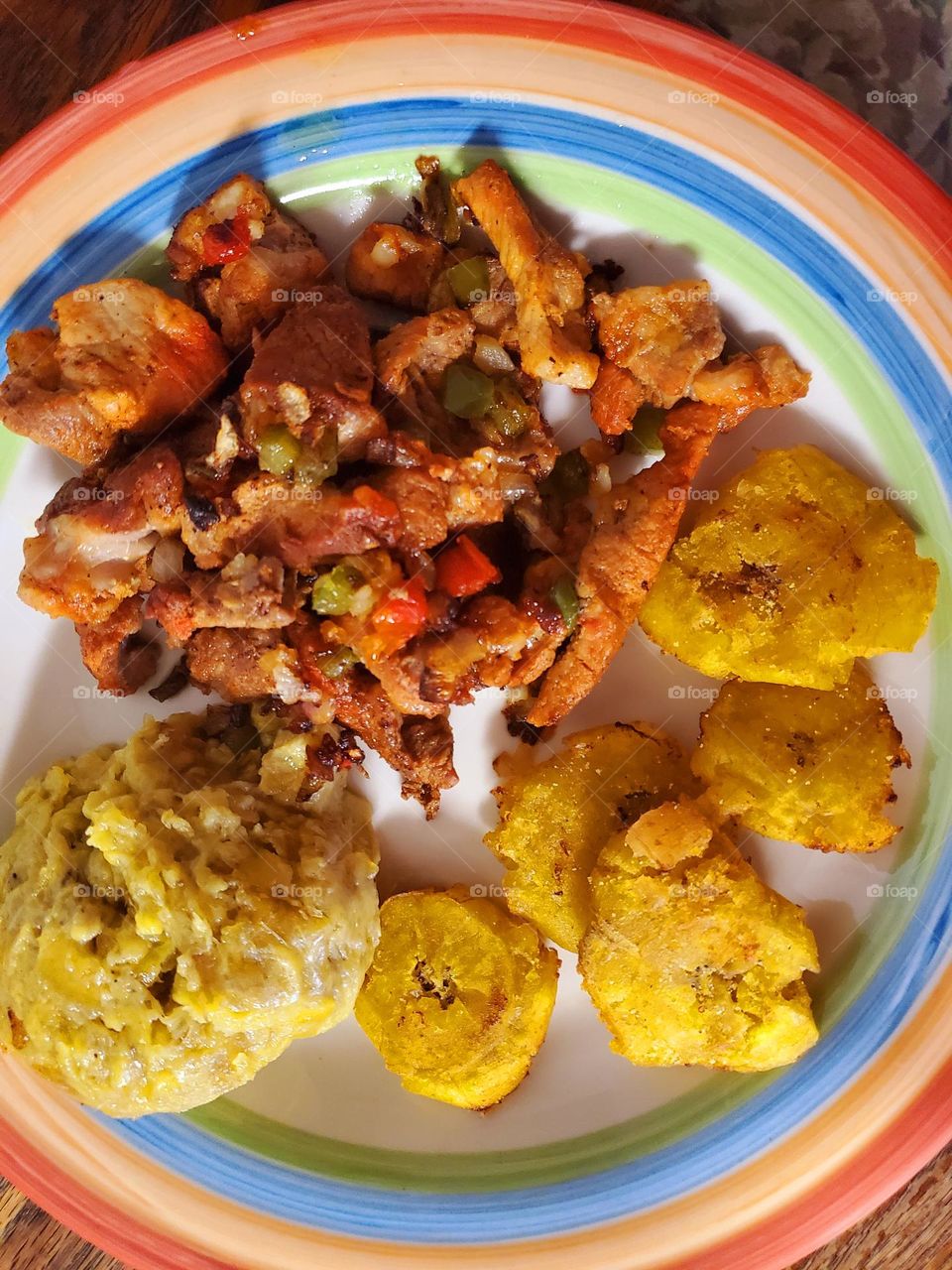 Mofongo de guineas Maduro, tostones de platanos y carne de cerdo frita con sofrito. Ripe banana mash, fried plaintains and fried pork with diced onions and peppers.