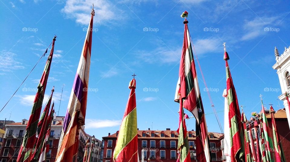 many colorful flags in a city and the blue sky
