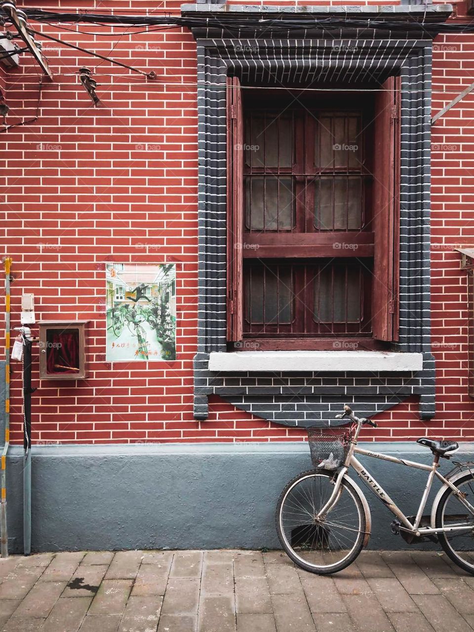 A beige rustic bicycle by a colorful red brick wall