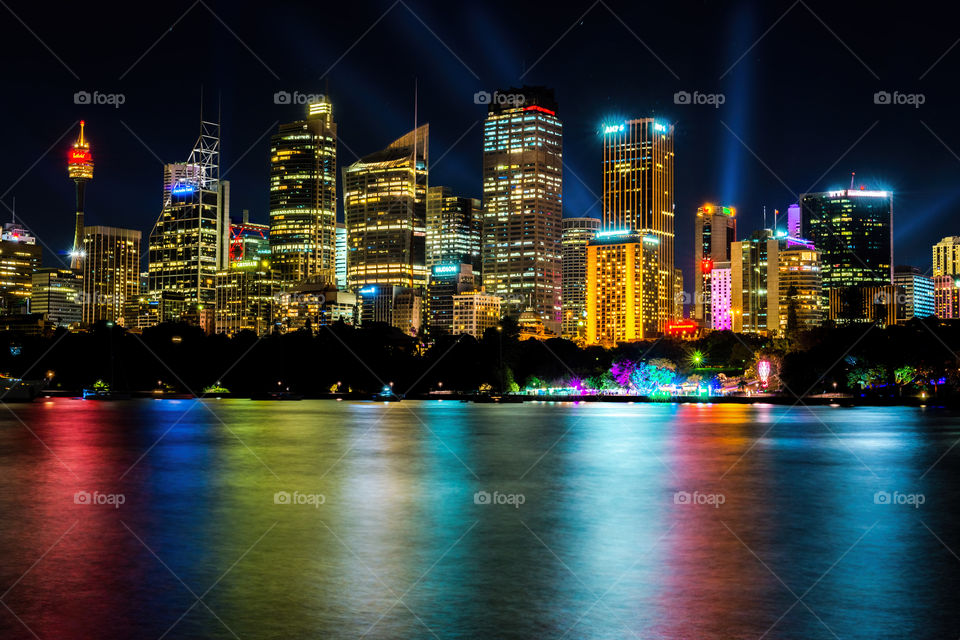 Sydney, Australia - May 26, 2016: Long exposure of city skyline by night from Mrs Macquarie's Chair, featuring light show.  High resolution vibrant image with colorful water reflections.