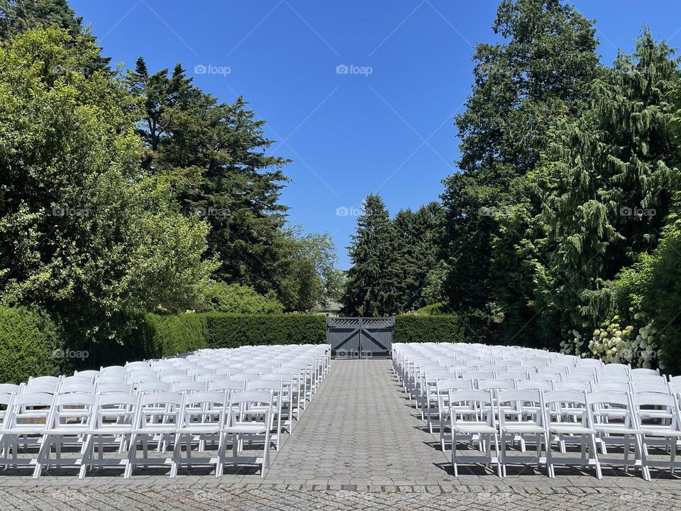 White chairs arranged in the beautiful sunny outdoors ready for a fun summer event. 