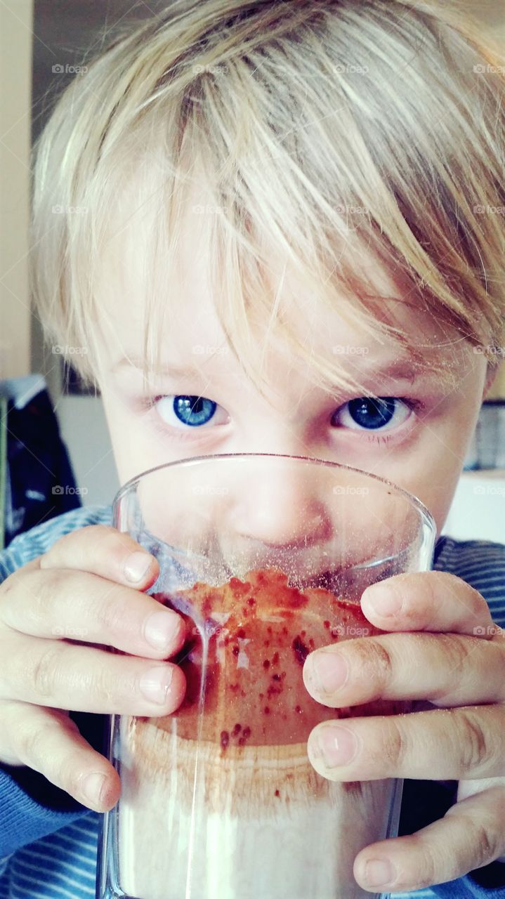 Boy with blue eyes drinking chocolate milk
