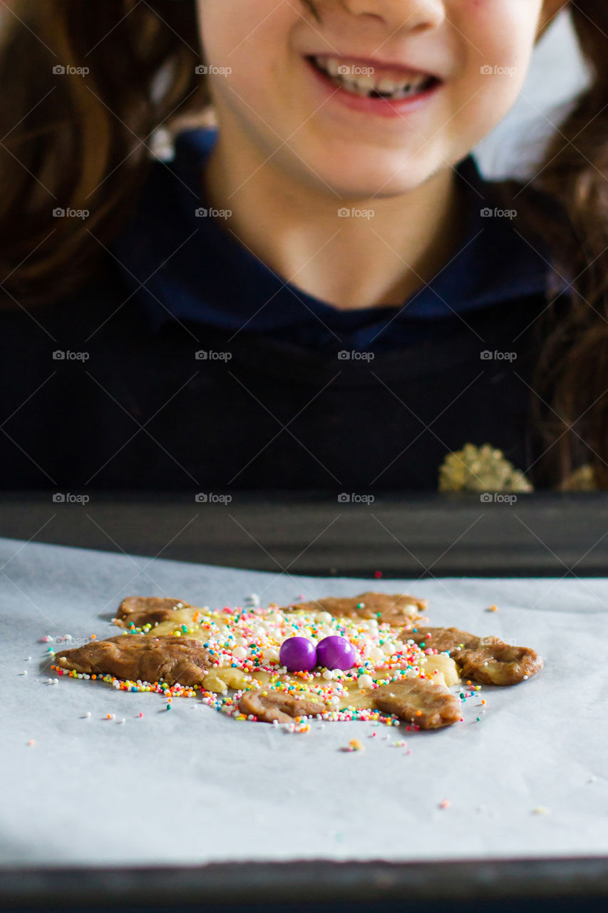 Having fun at home - we play and learn using cookies and decoration to bake and learn about hygiene email the corona virus at the same time. Girl holding her decorated cookie dough - ready to bake!