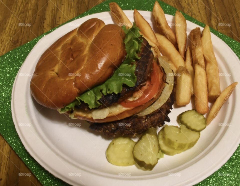 Double burger with the works and pickles and French fries on the side