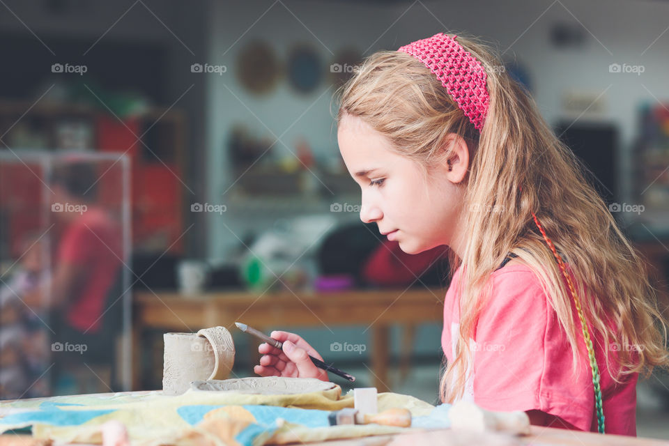 Side view of girl working on pottery