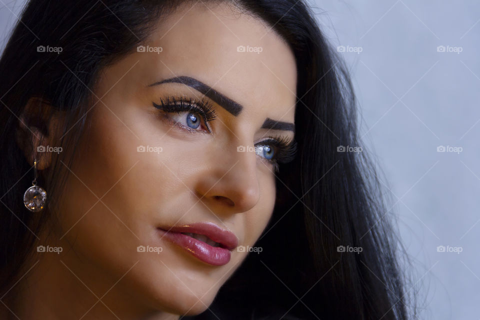 a portrait of a women with beautiful eyes looking in the distance. a girl with blue eyes and red lips