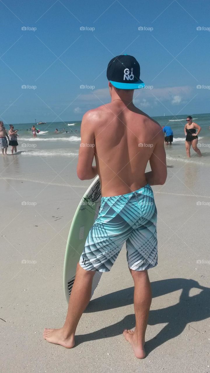 Boy checking out the beach for wake boarding in the summertime