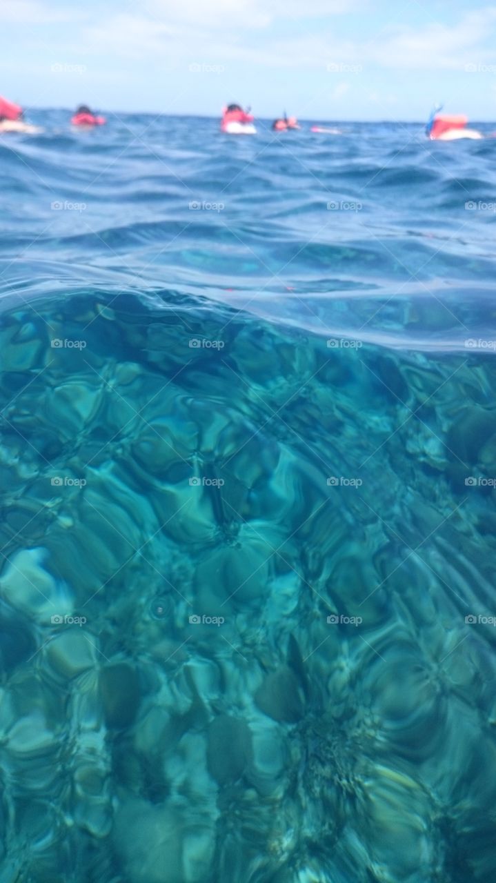 A shot of the water with coral reefs under. Bright ocean blue colors in the photo.
