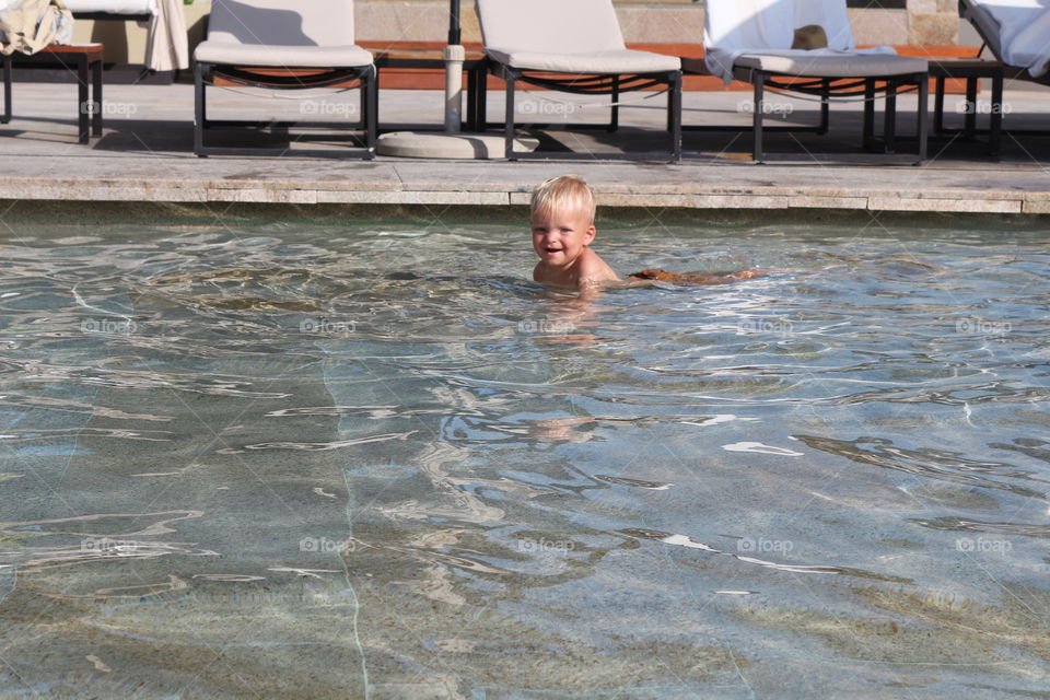 Cute blonde baby smiling and having fun at the pool 