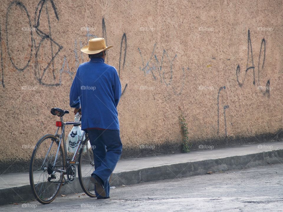 A back view of a Mexican man with a plastic shopping bag with plastic shopping and his bicycle in Ixtapan de la Sal, Mexic