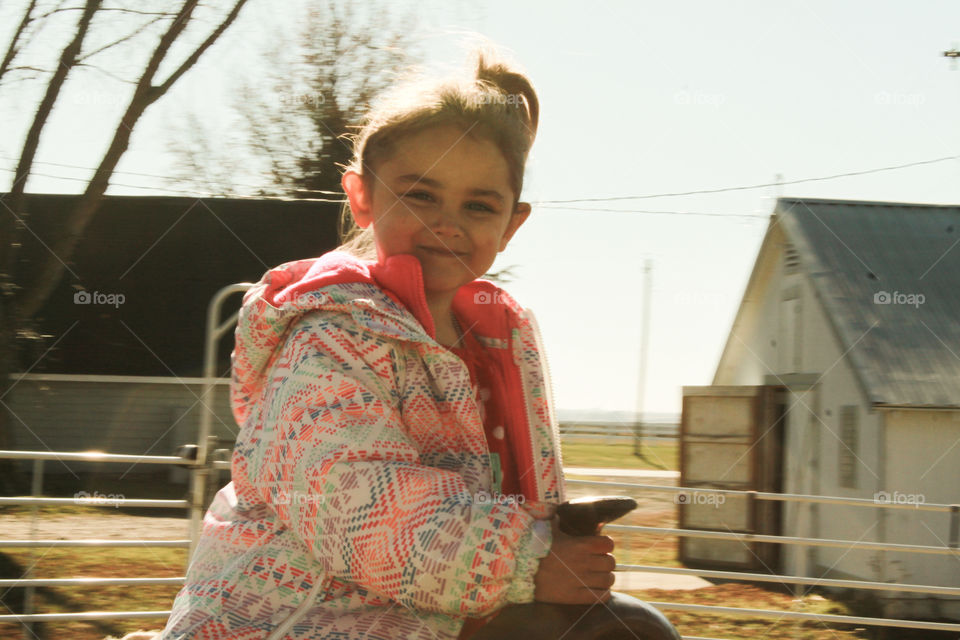Young Girl Horseback Riding On Farm Near Barn