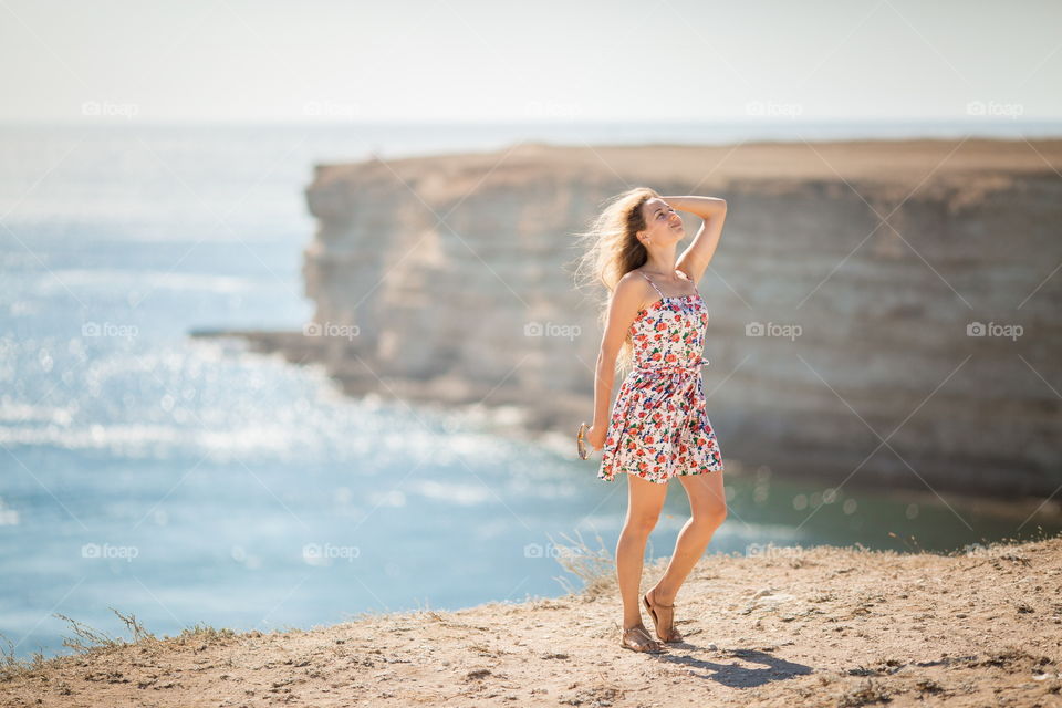 Portrait of beautiful young woman near the sea at sunset