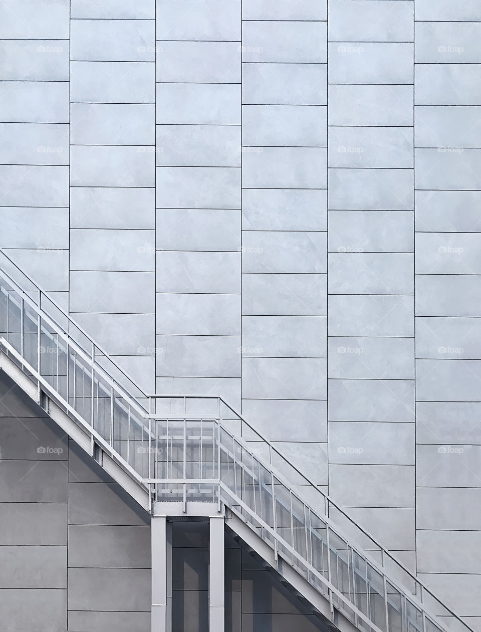 Metal stairs in front of grey brick wall background 