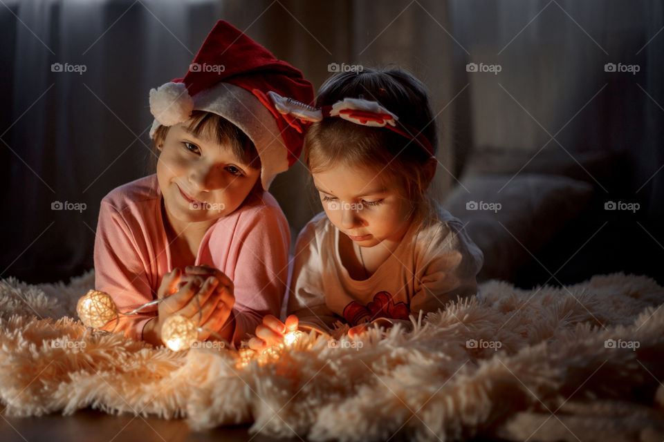 Little sisters reading a book at Christmas time 