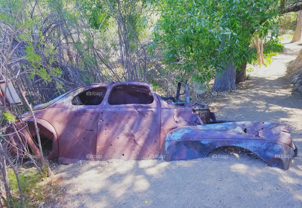 Old abandoned metal car carcass that people use for target practice.