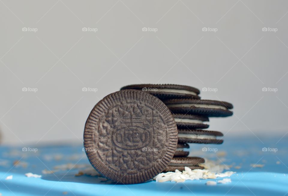 A stack of coconut Oreo thin cookies on a white and blue background with coconut shreds