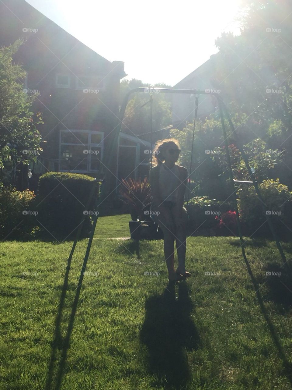 My beautiful daughter on the swing in the garden as the sun goes down in July. Hot weather and bbq