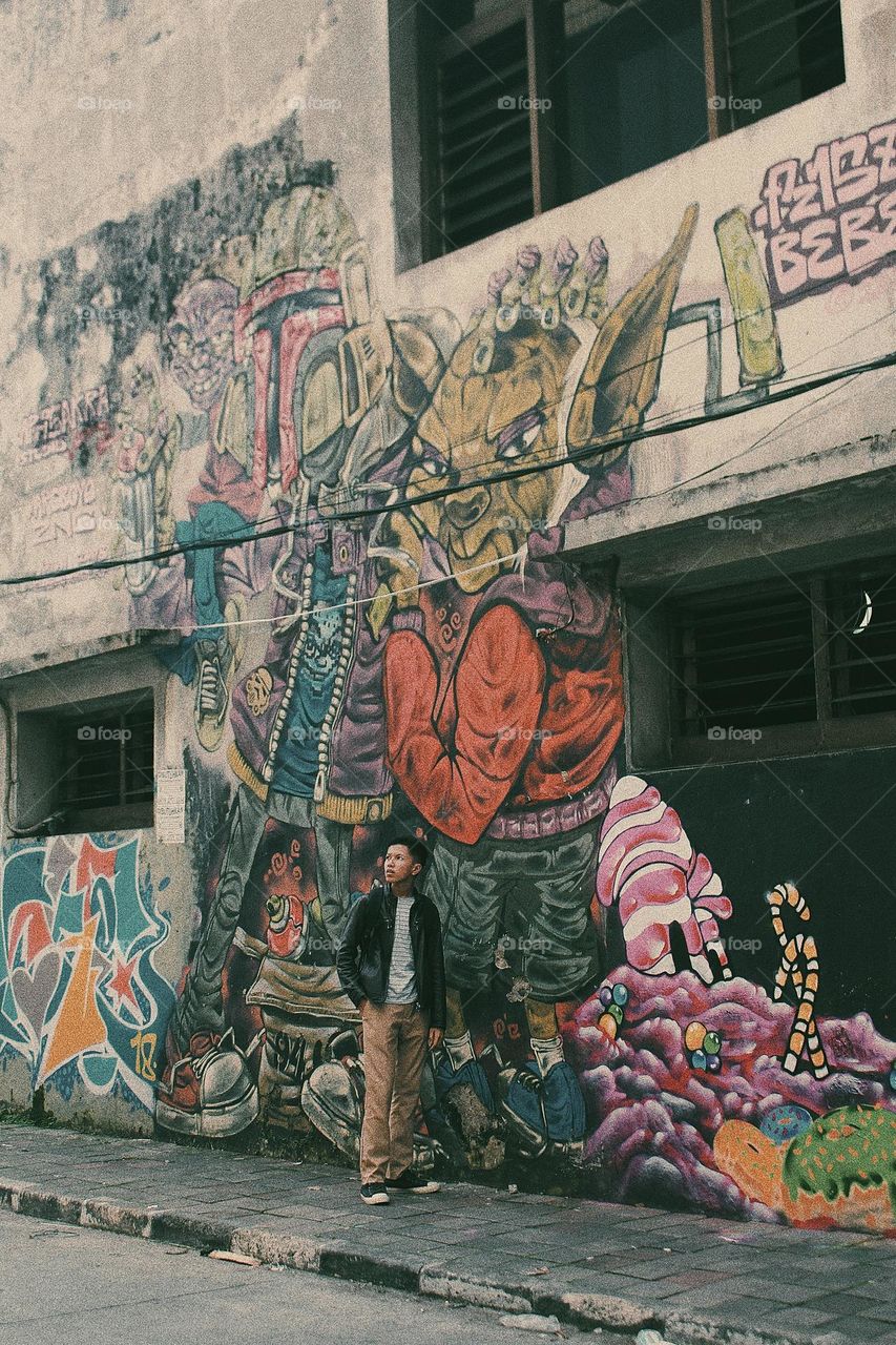 a man is standing around a building full of murals and graffiti