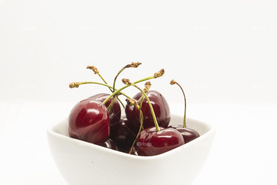 Delicious cherries in white bawl on white background