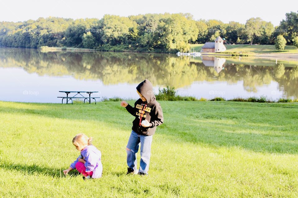 Amazing photo of two darling children playing in field looking for flowers and bugs! 