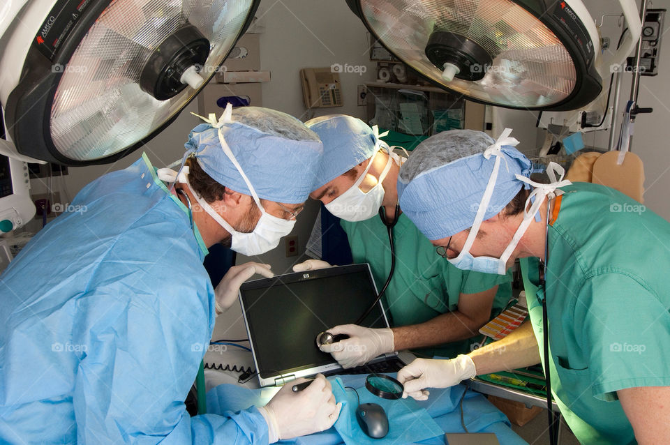 Three men operate on a computer in an emergency room hospital